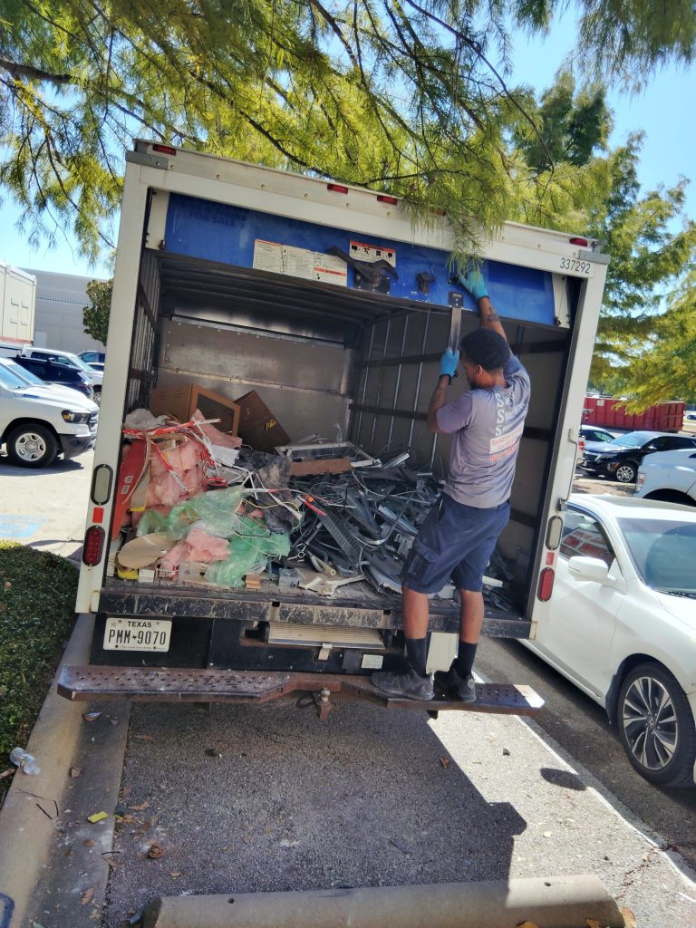 Professional junk removal and hauling services in Fort Worth with a mover loading debris into a large moving truck