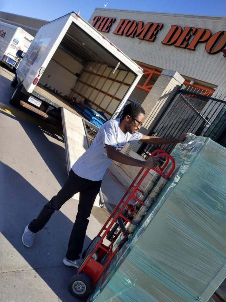 Professional movers in Fort Worth loading shrink-wrapped retail furniture into a moving truck at The Home Depot