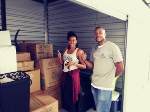 Happy customers and professional movers standing with stacked U-Haul boxes in a Fort Worth storage unit